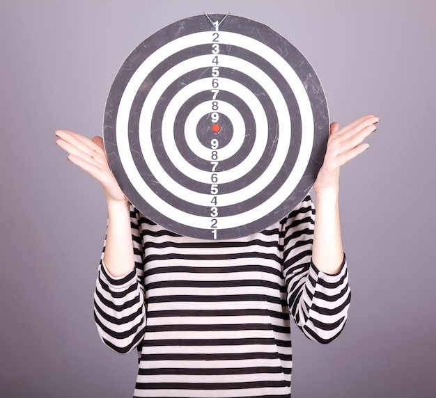 Girl with dartboard in place of head. 