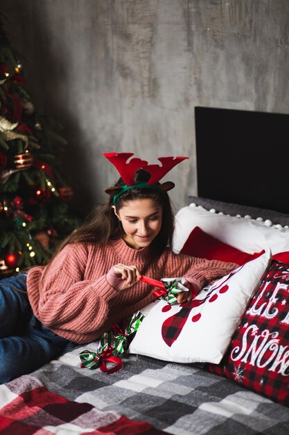 Ragazza con corna di cervo sullo sfondo dell'albero di natale.