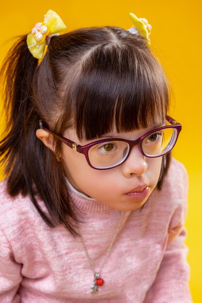 Girl with disorder. Resolute little dark-haired lady wearing pretty necklace on pink sweater while actively thinking