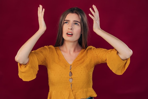 Girl with a displeased expression looks up and holds her hands near her head