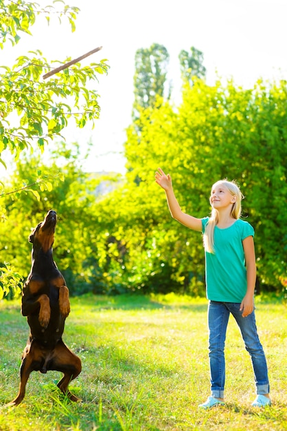 Girl with dobermann in summer park.