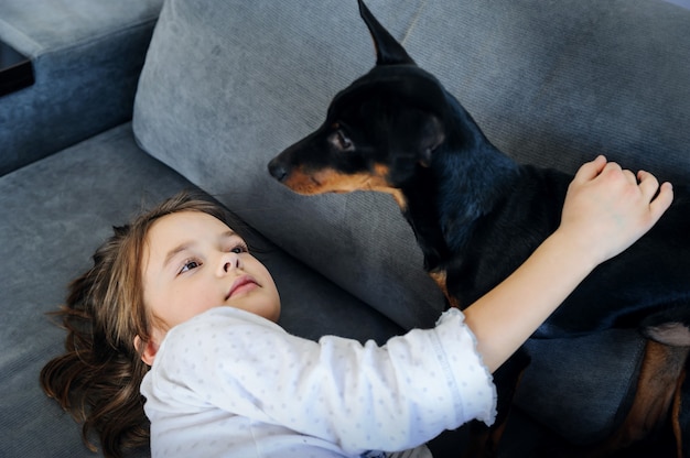 The girl with the dog is playing on the sofa.