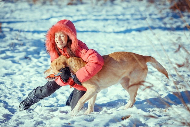 Girl with a dog Labrador puppy playing in winter outdoors fun