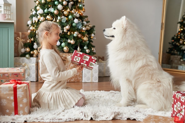 Ragazza con un cane vicino all'albero di natale sulla scena di natale