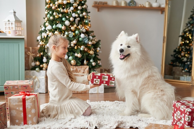 크리스마스 장면에서 크리스마스 트리 근처 강아지와 소녀