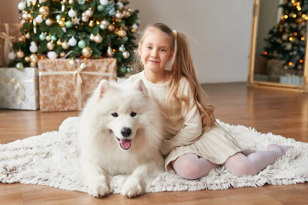 Ragazza con un cane vicino all'albero di natale