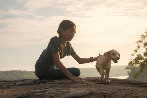 girl with dog sitting by lake against sky
