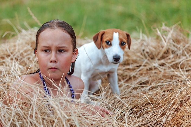 干し草のソフトフォーカスに座っている犬と女の子