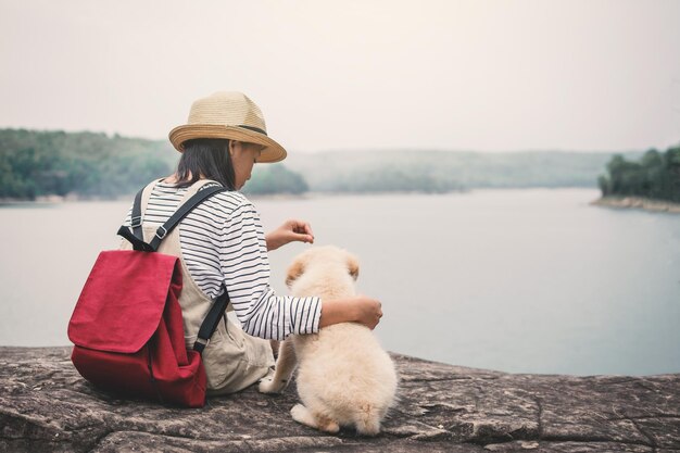 写真 空に逆らって湖岸の岩の上に座っている犬の女の子