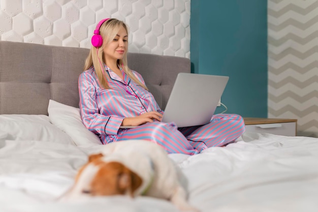 A girl with a dog watching a movie on a laptop with headphones pets and pet friends for people