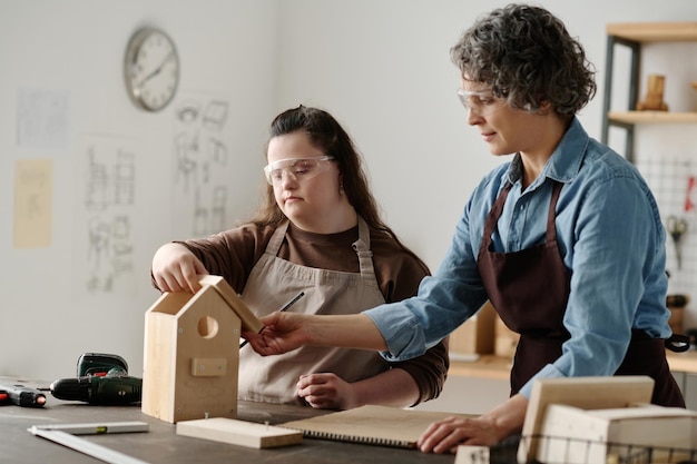 ワークショップで大工と一緒に巣箱を作るダウン症の女の子