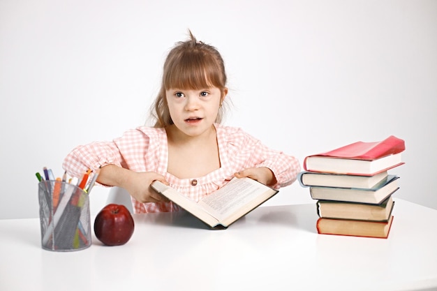 Ragazza con sindrome di down che studia mentre si siede alla scrivania a casa