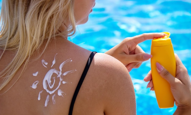 Ragazza con un disegno del sole sulla schiena con crema solare. relax in piscina. messa a fuoco selettiva