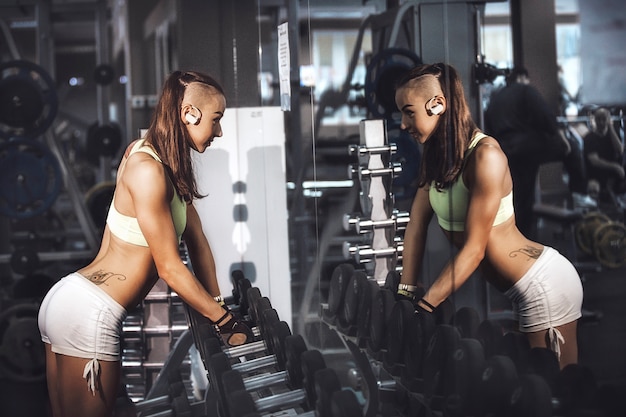 Girl with dumbbells in a sports club