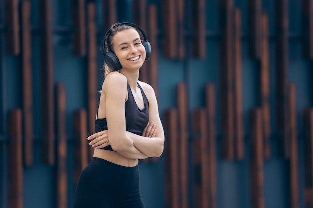 Girl with earphones standing with crossed arms smiling