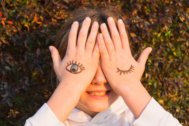 Girl with eye tattoos on hand palm covering her eyes