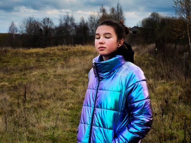 Foto ragazza con gli occhi chiusi che indossa una giacca lucida a terra