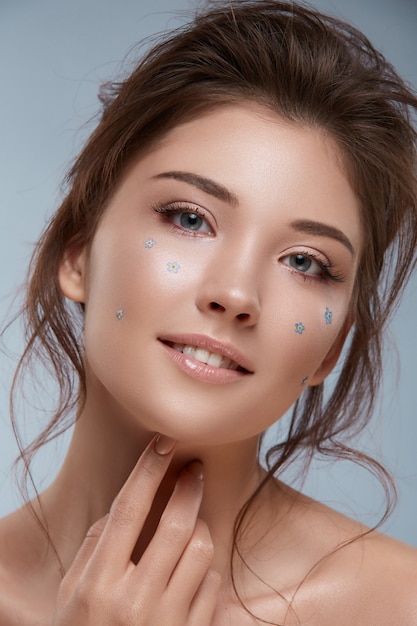 Girl with fancy hairstyle and flowered make-up looking to the camera