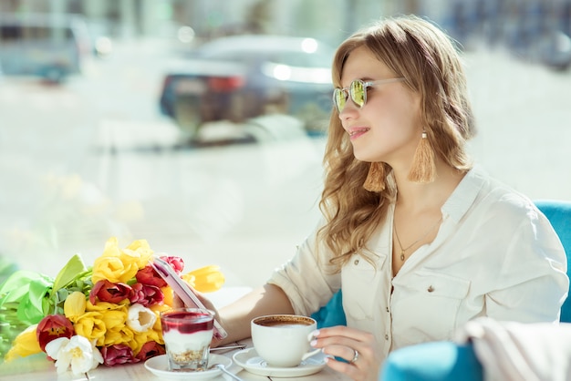 花、コーヒー、ヨーグルト、カフェで電話を持つ少女