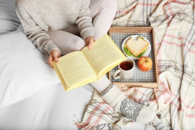 Girl with food reading book on bed