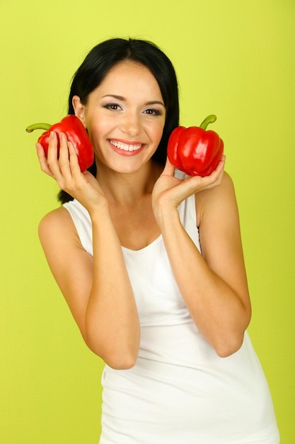 Girl with fresh peppers on green background