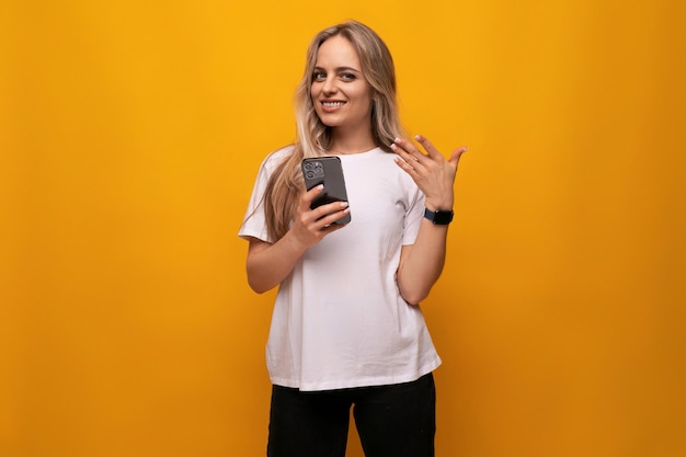 Girl with a gadget sits on the internet on an orange background