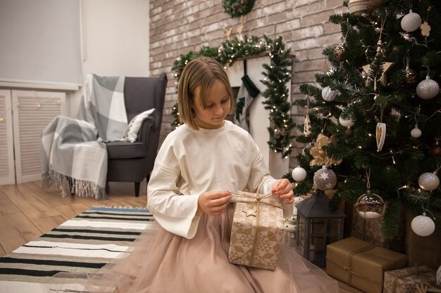 Girl with a gift at the Christmas tree, soft focus