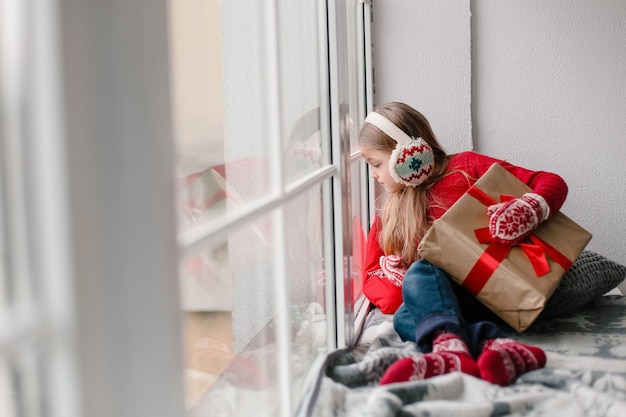 Photo girl with a gift looking out the window