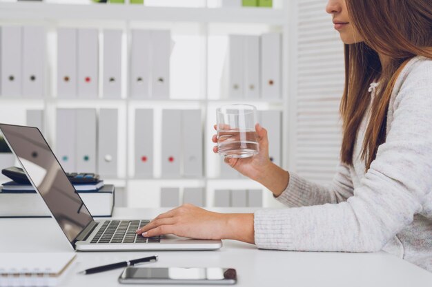 Girl with glass of water typing