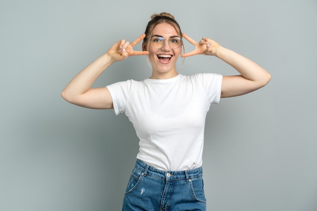 girl with glasses makes a gesture of victory