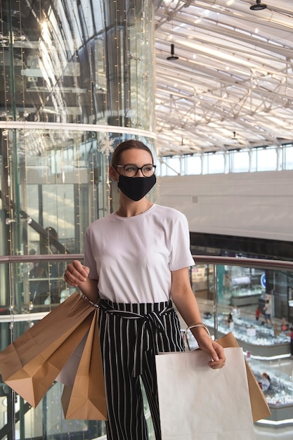 Girl with glasses and a protective mask in a mall with purchases
