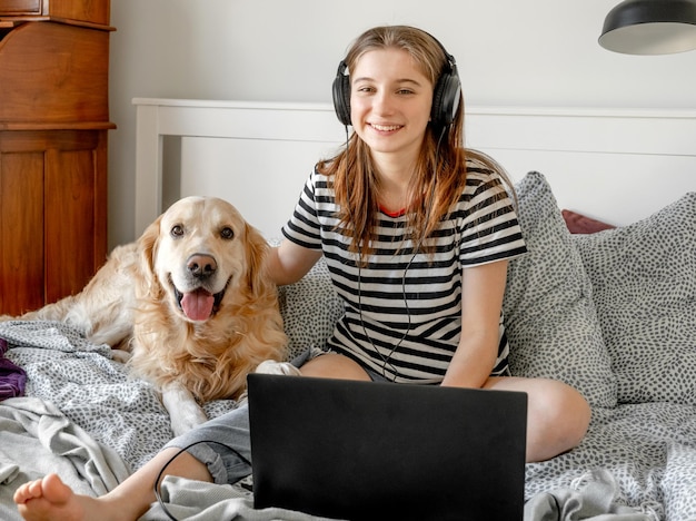 ベッドでゴールデンレトリバー犬を持つ少女