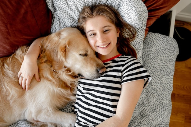 ベッドでゴールデンレトリバー犬を持つ少女