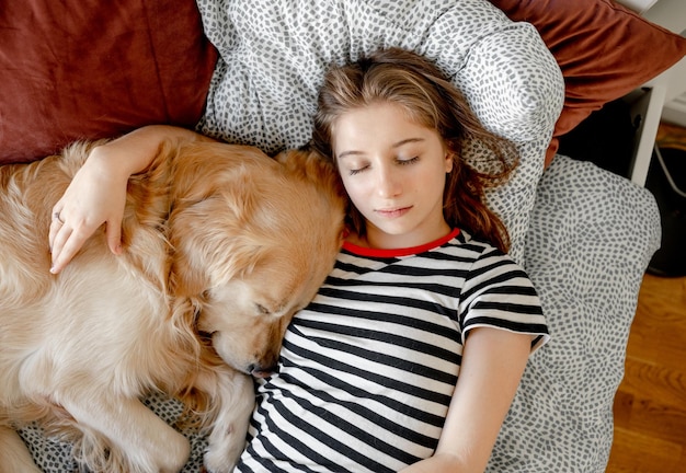 Girl with golden retriever dog in bed