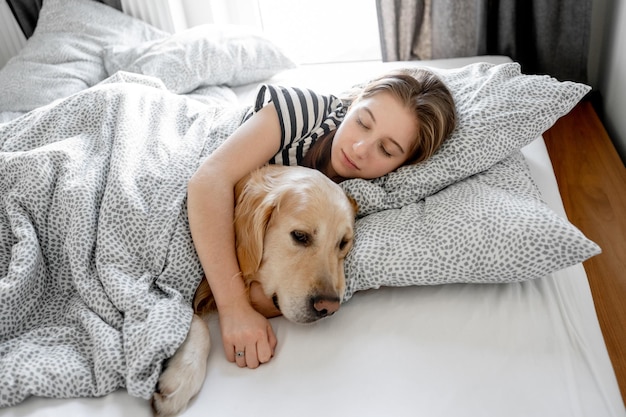 Girl with golden retriever dog in bed