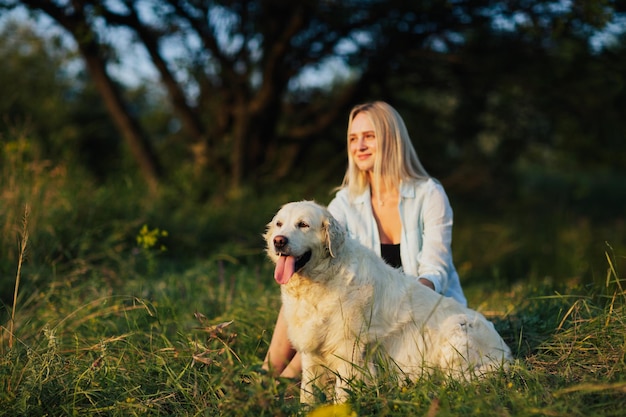 girl with golden retriever dog sitting in the park