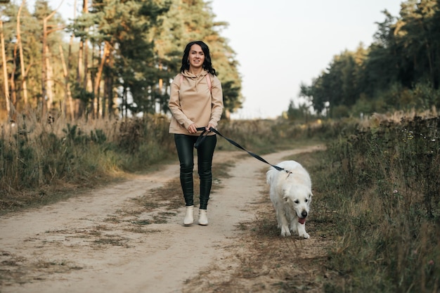 Girl with golden retriever dog walking on forest path