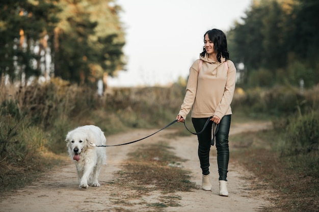 Photo girl with golden retriever dog walking on forest path