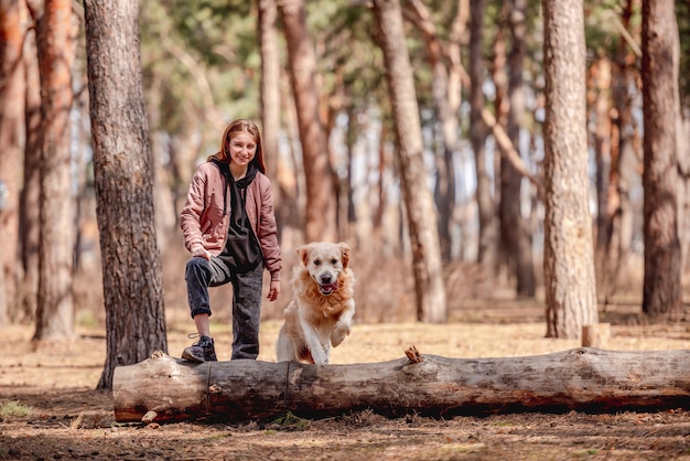 Girl with golden retriever dog in the wood