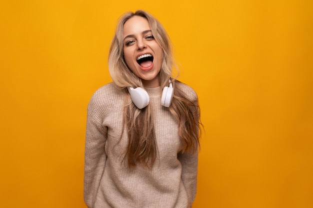 Girl with a grimace in headphones on a yellow background