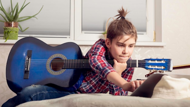 A girl with a guitar on her lap is lying on a bed and the word music on the side of her chest.