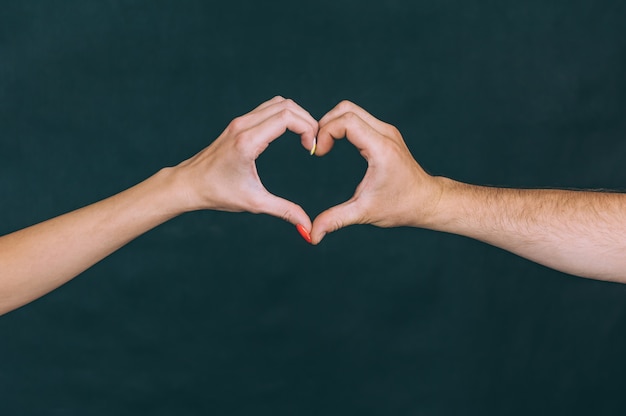 Girl with a guy show hands a sign in the form of a heart