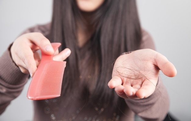 Girl with hair loss holding comb.