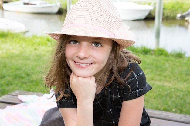 A girl with a hand under the chin with a hat