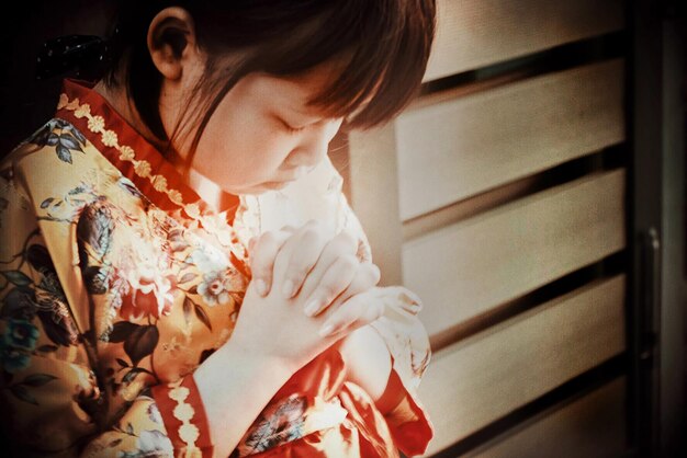 Photo girl with hands clasped praying while standing outdoors