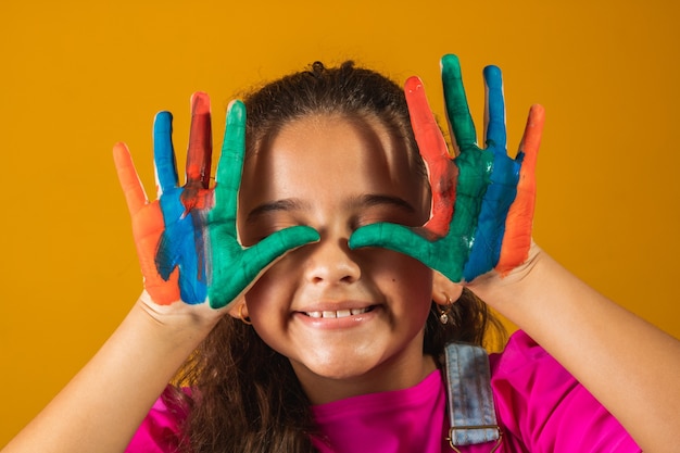 Girl with hands painted in colored paint. Girl with hands on eyes painted