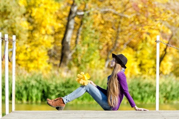 Girl with hat sitting on the dock