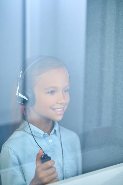 Girl with headphones in special room behind glass