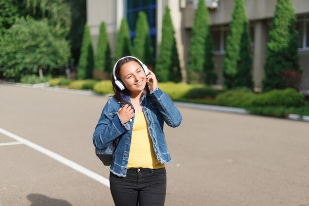 晴れた日に公園を散歩して音楽を聴くヘッドフォンを持つ少女