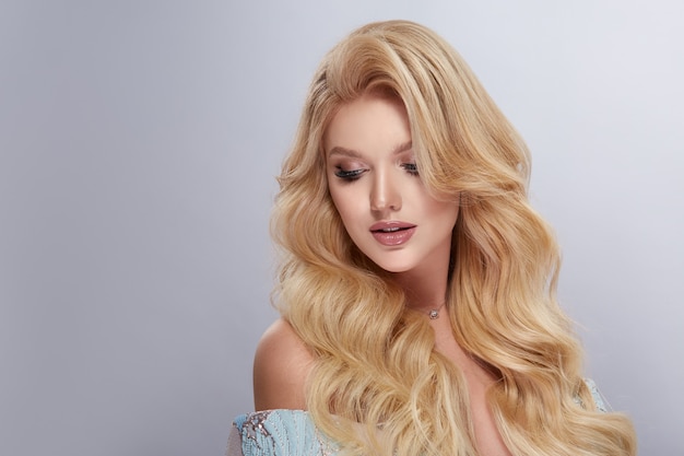 Girl with healthy and wavy long blondie hair looking down